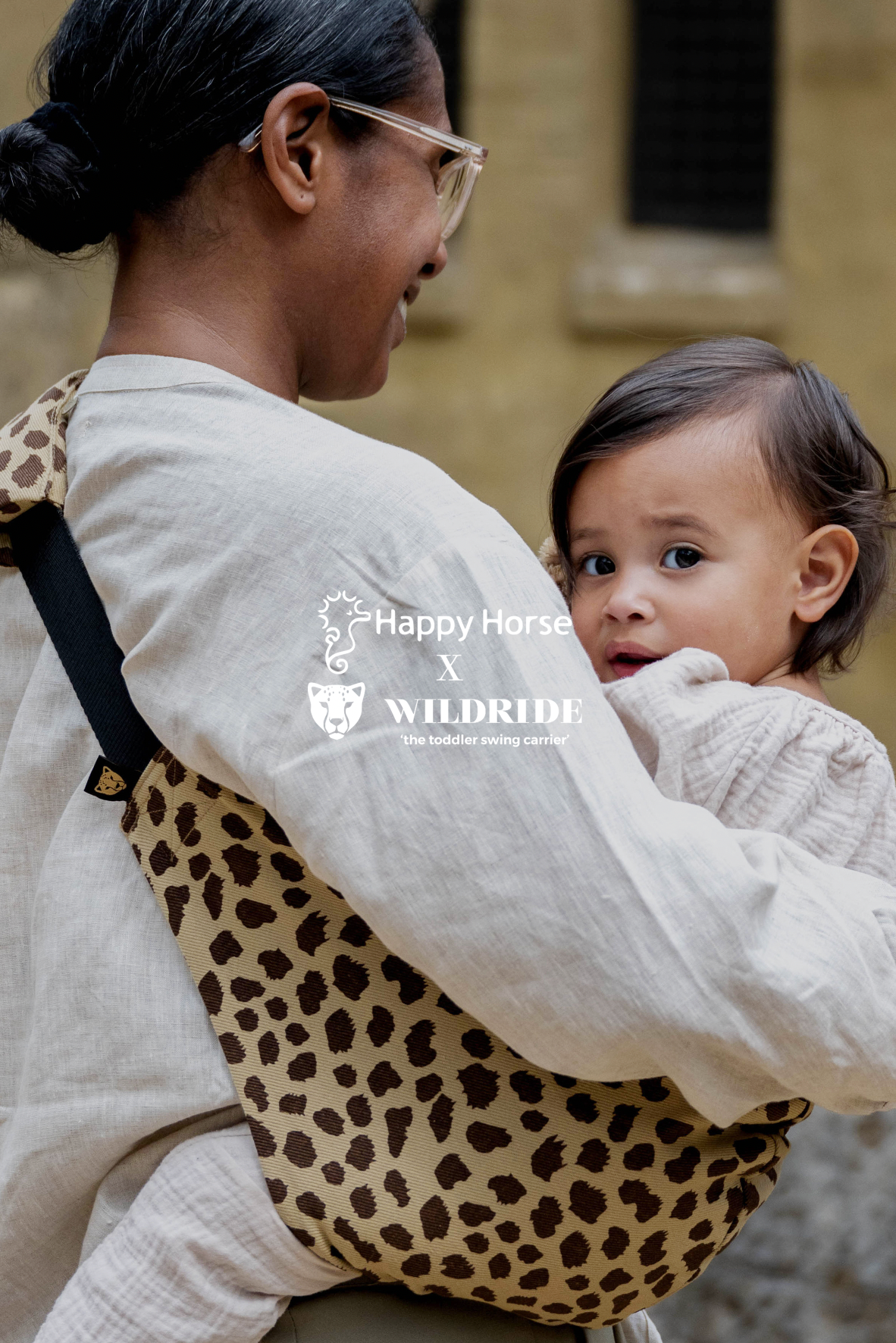 Parent carrying a toddler in the leopard print Wildride toddler carrier from the Happy Horse x Wildride collaboration.