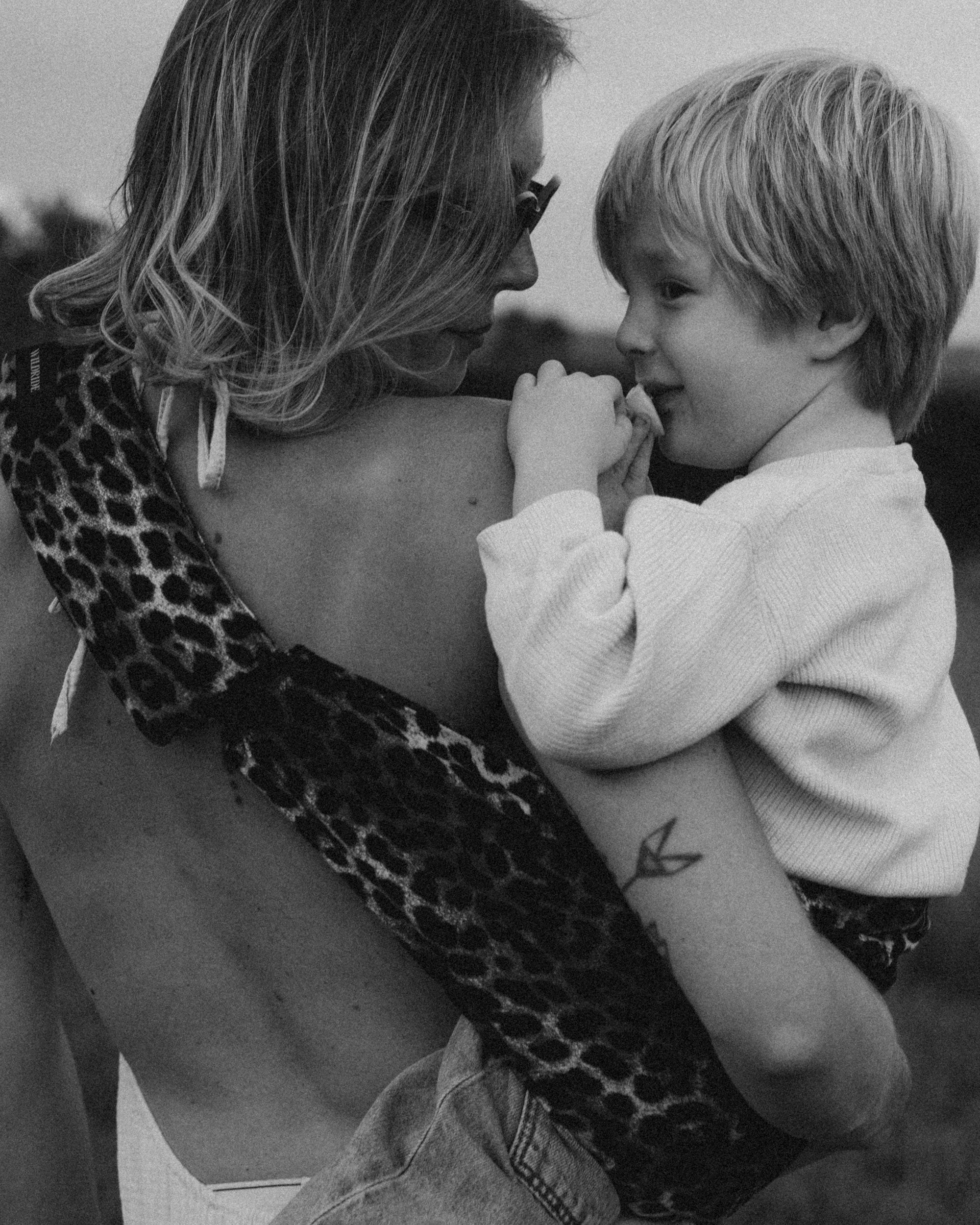 Mother carrying her child in a Wildride carrier during a quiet walk through a field