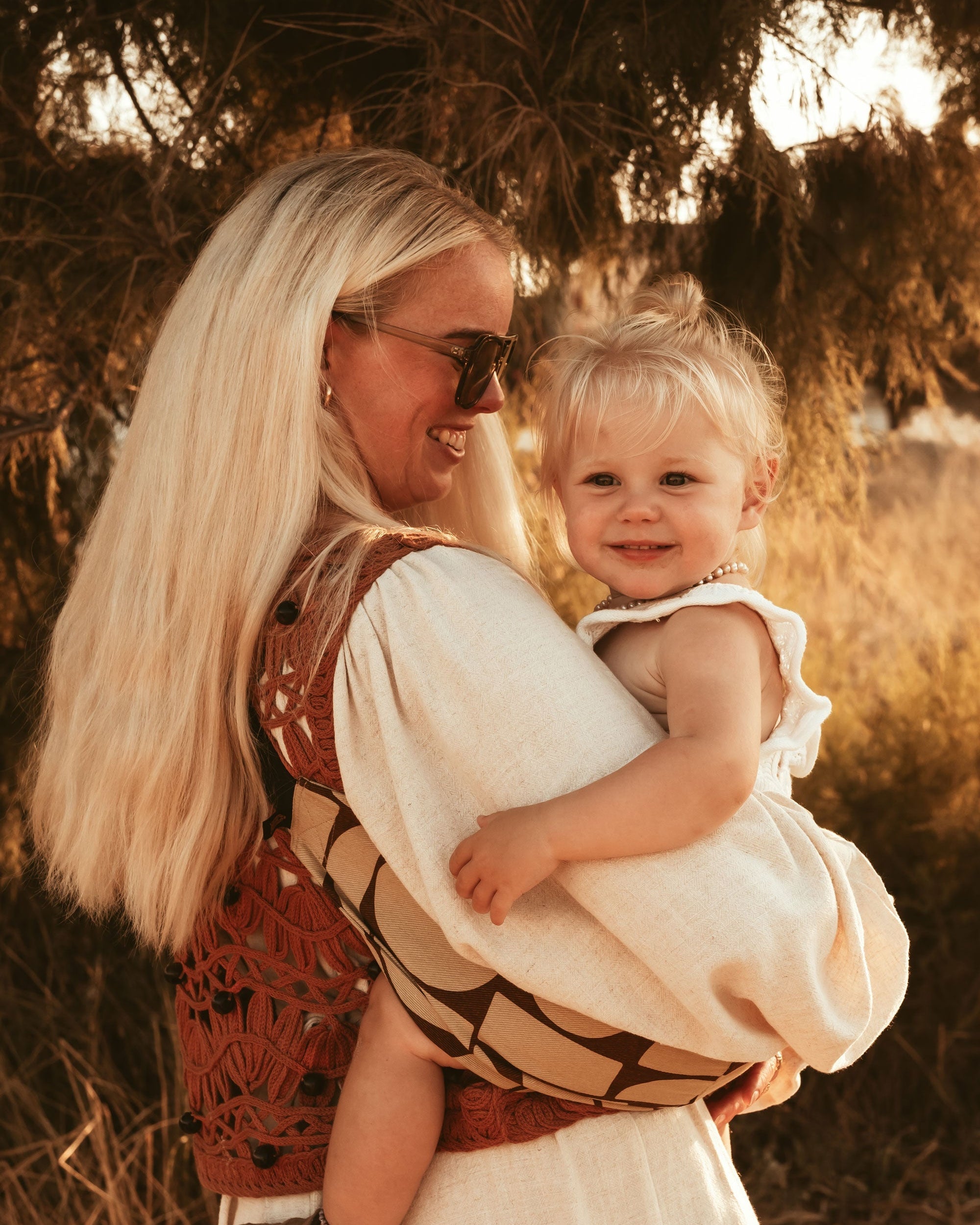 Parent carrying toddler in Wildride toddler carrier outdoors